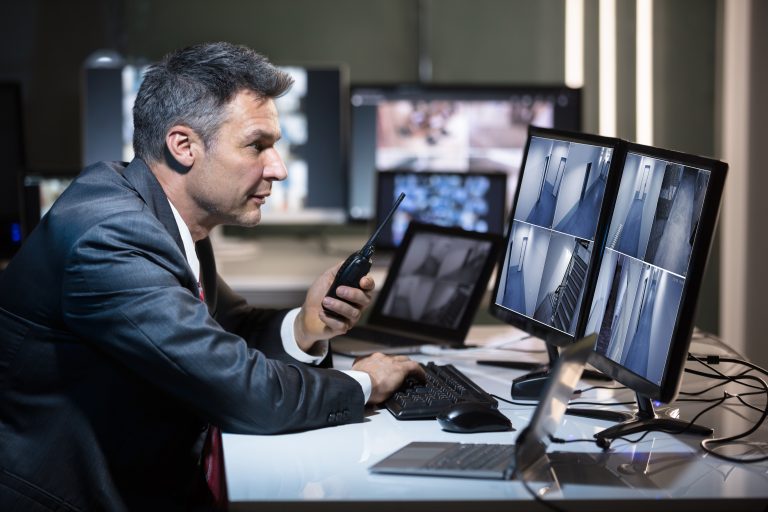 Middle-aged man sitting in front of many monitors providing commercial security solutions for New York City businesses