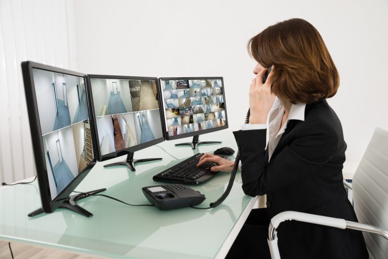 Woman in black suit checking security camera installation calling on phone